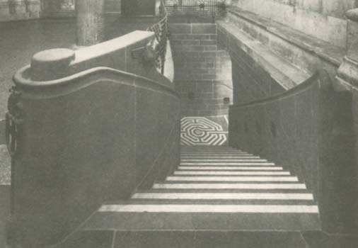 A stone staircase leading down into a dark, arched tunnel or passage.
