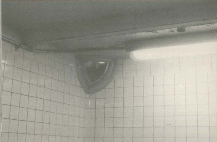 A security camera mounted in the corner of a tiled room