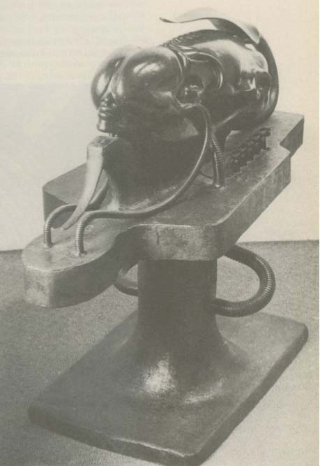 A sculpture of a metallic, insect-like head mounted on a mechanical base