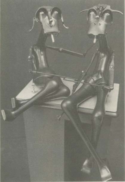 Two metallic, humanoid figures sitting at a table, smoking.